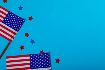 Overhead view of small america flags on sticks by glitter stars by copy space over blue background