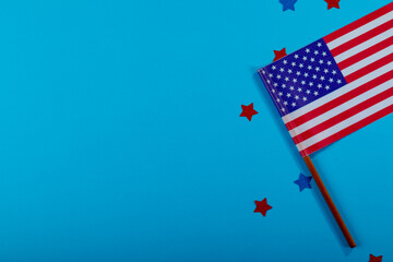 Overhead view of small america flag on stick by glitter stars by copy space over blue background