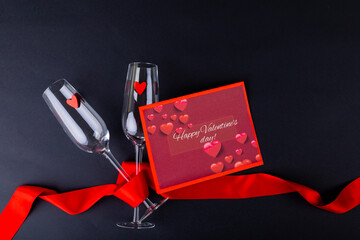 Gift card with happy valentines day text by champagne flutes wrapped with red ribbon