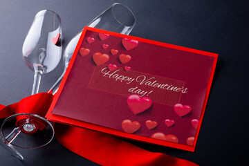 Gift card with happy valentines day text by champagne flutes wrapped with red ribbon
