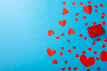 Overhead view of red present amidst red heart shapes scattered by copy space on blue background