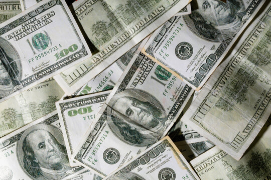 Overhead view of scattered hundred dollar bills with famous historic personality