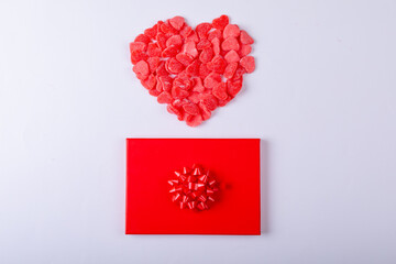 Red heart shape candies over gift box around copy space on white background