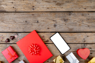 Smartphone with blank screen showing copy space arranged by gift boxes on wooden table