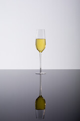 Closeup of champagne flute with reflection on glass table, drink against white background