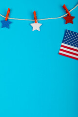 Clothespins holding star shapes on string by usa flag with copy space on blue background