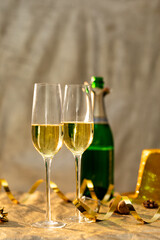 Closeup of champagne flutes by golden ribbon in front of bottle on table