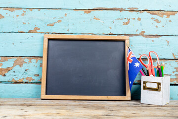 Blank writing slate by australian flag and desk organizer against wooden wall, copy space © wavebreak3