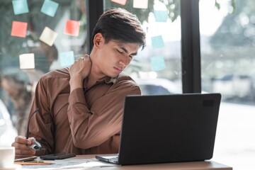 Young Man Suffering from Neck Pain While Working at Laptop Computer