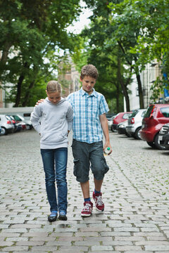 Boy and girl walking together on cobblestone street in Berlin in summer