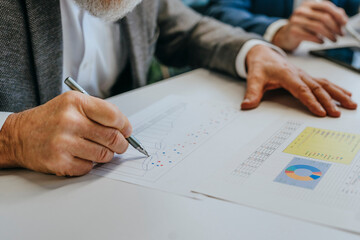 Businessman analyzing charts and diagrams at office desk close up