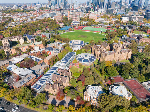 Aerial view of historic buildings, a sports oval and distant city skyline