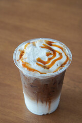  top view ice caramel macchiato coffee in a plastic cup, placed on a wooden table background, drink, food, copy space