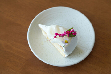 top view slice of coconut cream cake, pink and purple flowers in white ceramic dish on wooden background, dessert, food, fashion, decor, copy space