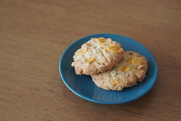 Two whole-grain cookies are stacked on top of each other on a small black and blue ceramic plate on a wooden table background, food, snack, sweet, copy space