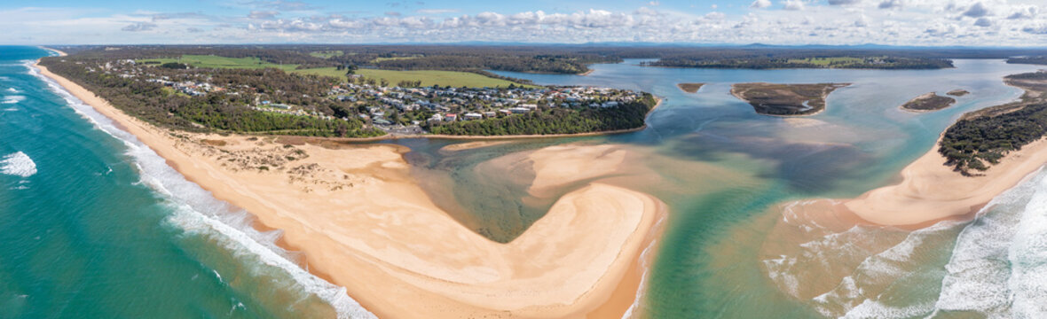 Aerial panorama view of a coastal town and inland river mouth partially blocked by sand bars