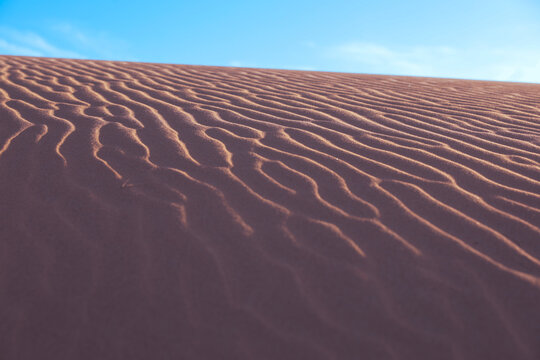 Rippled sand dunes and blue sky close up