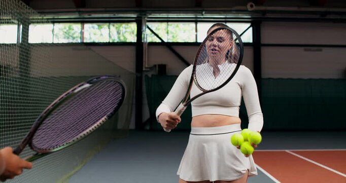 Close-up of a tennis player with a racket and balls in her hands.