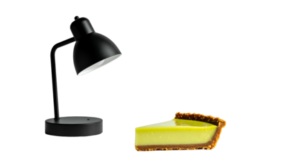 A black desk lamp illuminates a slice of a bright, creamy pie with a graham cracker crust. The objects are isolated