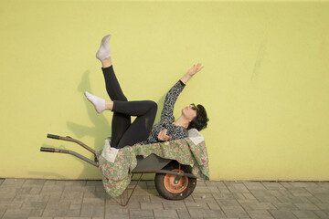 woman performing acrobatic pose in wheelbarrow with legs raised, black leggings and white socks, sunglasses and floral quilt
