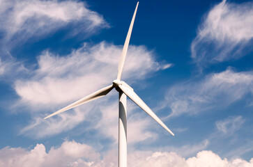 Wind turbines lined in a sunny mountain landscape, blending nature with clean energy.