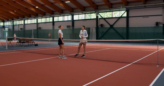 The girls go to the center of the court before the match and toss a coin to decide who will serve first.