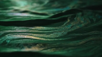 Close-up of flowing, textured green material with hints of gold and dark shadows - Powered by Adobe