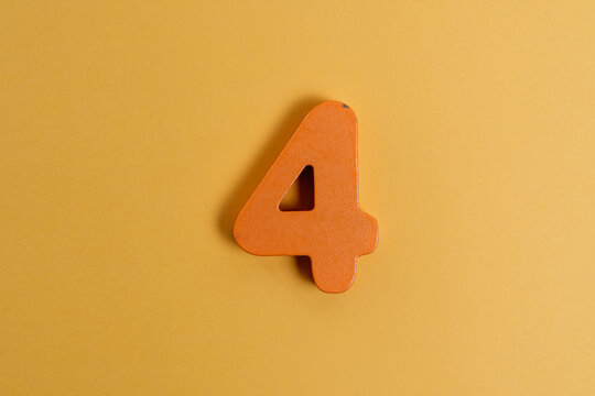 Orange wooden number four representing concepts of learning, education, and childhood numeracy
