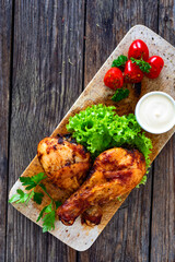Roasted chicken drumsticks with mayonnaise on wooden table. Top view