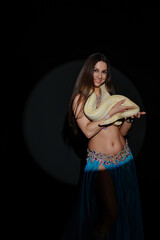 Woman dances with a snake during a performance in a dark setting