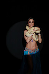 Woman dances while holding a snake during a performance in a dark setting at a cultural event