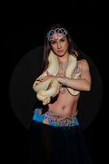 Woman performs dance with a snake in a dark setting during a cultural event in the evening