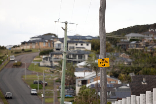 Yellow caution sign directing buses to turn right on top of hill in residential area