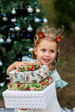Happy young Australian child holding pile of gift wrapped Christmas presents at Christmastime