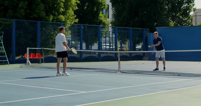 Two guys toss the ball over the net. .