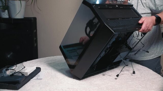 Flipping computer case for cable management, man carefully turns case onto its side to access the back for organizing cables
