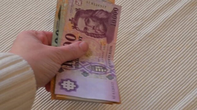 Close-up video of a female hand taking and removing Hungarian forint banknotes on a white background with Copy Space. Strong financial concept representing spending, loss, payment, inflation, expenses