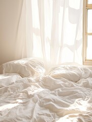 White bed linens with two pillows and crumpled duvet on an unmade bed, sunlight streaming through sheer curtains in a bright, tranquil bedroom interior during morning