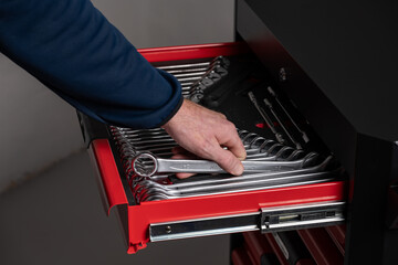 Hand selecting wrench from organized tool drawer