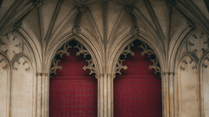 Fototapeta premium Gothic arched doors with red wooden panels and stone vaults