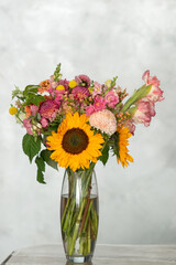 Vibrant bouquet with sunflowers, pink roses, and mixed floral arrangement in glass vase