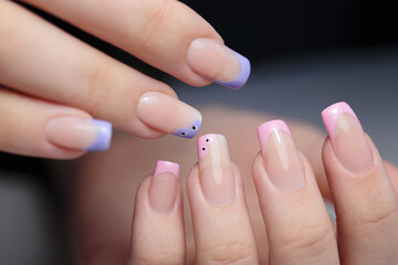 Stylish nail design with pink and purple tips and unique patterns in a beauty salon setting