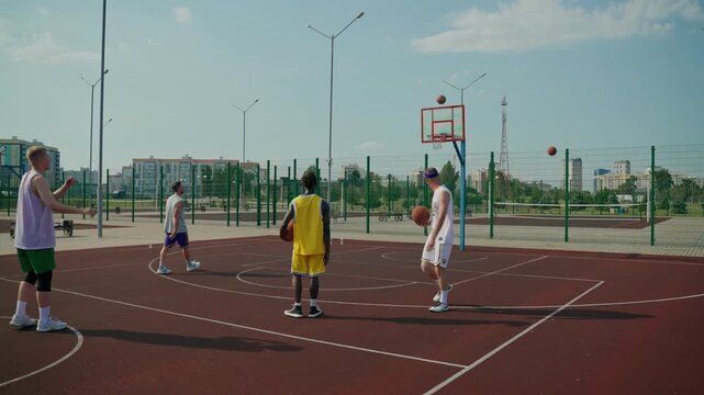 Basketball players practice three-point shots during training. The basketball players practice shooting into the basket, celebrating good throws during training.