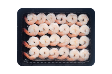Top view of frozen cooked peeled white shrimp arranged in rows in a black plastic tray isolated on a transparent background.