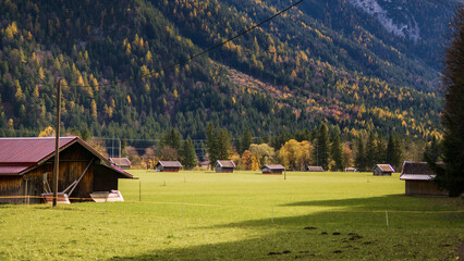 Alpine meadow with wooden huts in a mountain valley.