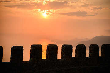 Sunset overlooks sea from historic fortress wall of Antalya. Fortress walls,Turkiye. Observation deck and battlements. Landscape of old fortress walls on Mediterranean coast. Tourism, historical sites