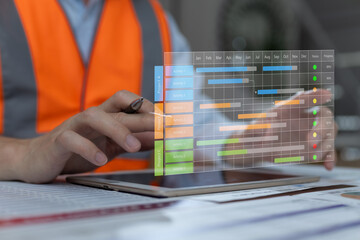 Construction manager using digital tablet to monitor Gantt chart project timeline. Concept for smart construction planning, scheduling, workflow management, and digital project control.