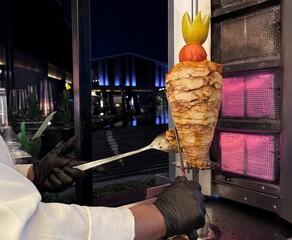 Cutting from a small shawarma skewer outside with the chef