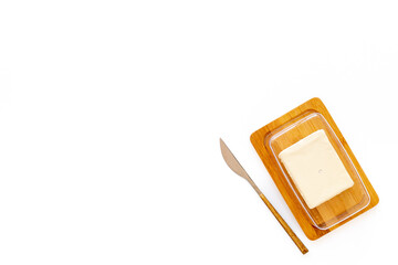 Block of fresh butter in wooden butter dish and a knife, top view