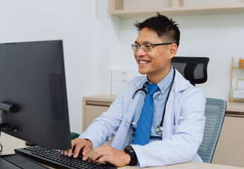 doctor is sitting at  desk with  computer and smiling
